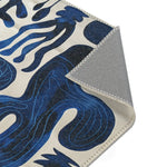 Indigo Desert Dreams rug corner folded showing grey non-slip backing with blue abstract botanical pattern on cream face