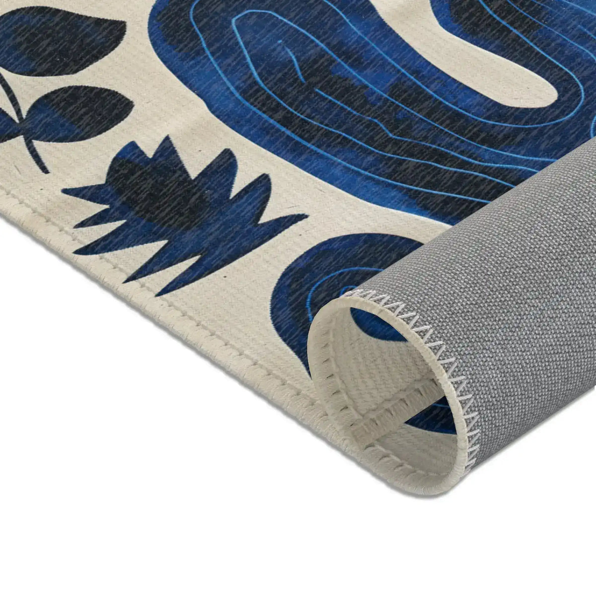 Indigo Desert Dreams rug edge rolled corner showing grey backing and blue leaf cactus pattern detail close-up