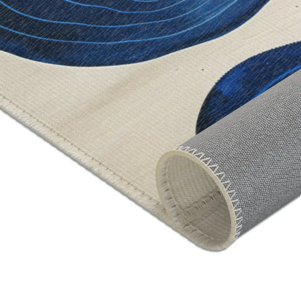 Indigo Desert Dreams rug tightly rolled corner showing cream edge binding and grey latex backing texture