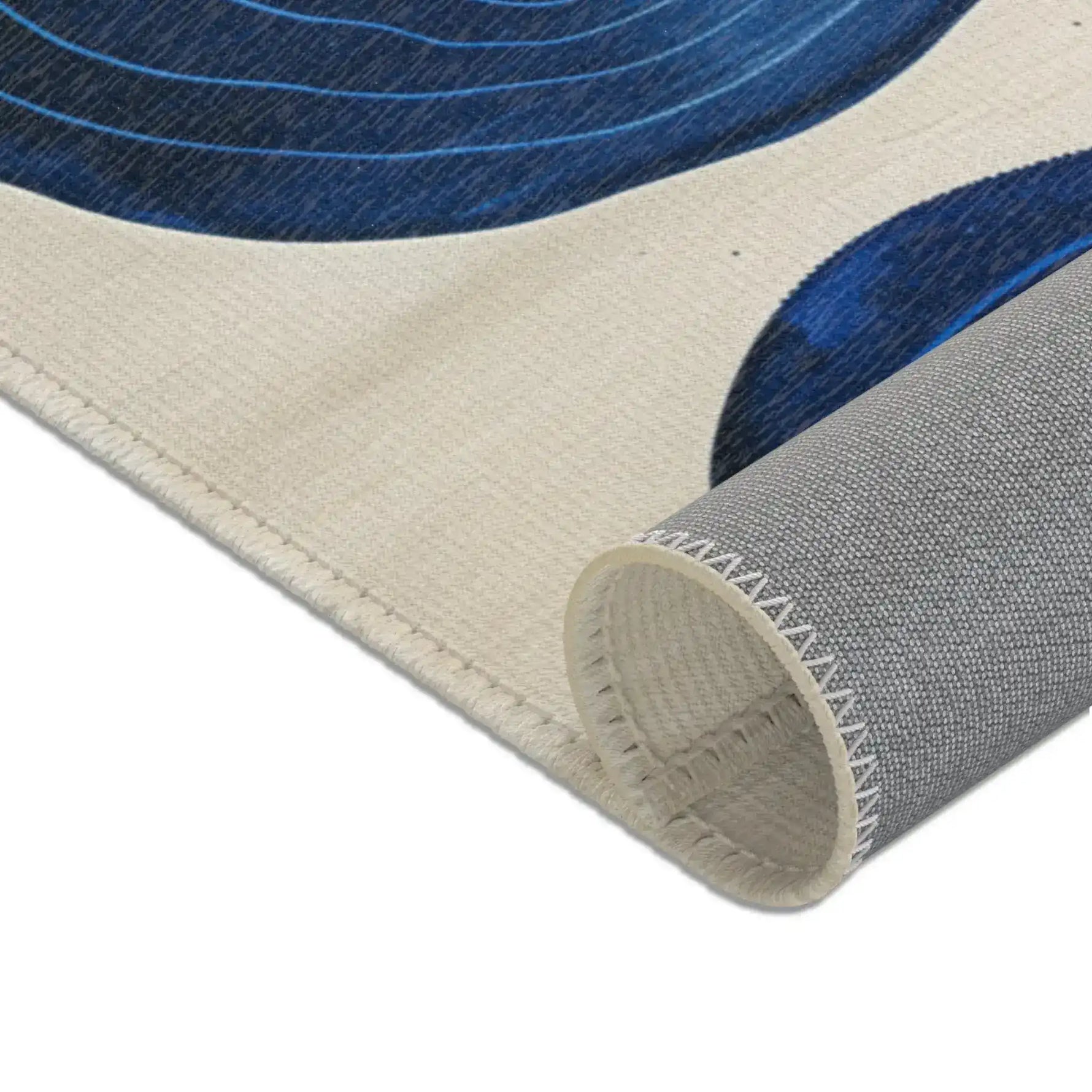 Indigo Desert Dreams rug tightly rolled corner showing cream edge binding and grey latex backing texture