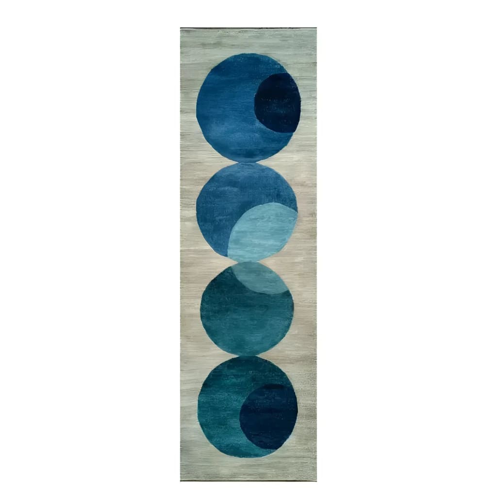 The Indigo Orbit Hand Tufted Wool Rug Runner features a contemporary design with overlapping blue circles against a neutral background. This area rug is perfect for adding a modern touch to your living room, hallway, or kitchen. Made from high-quality wool, it serves as an elegant hallway runner rug, suitable for both large living rooms and cozy spaces.