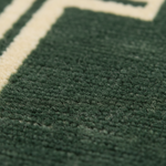 Close-up of a green textured rug with white lines