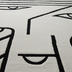 Close-up of a textured rug with black line art on a light gray background