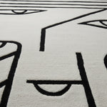 Close-up of a textured rug with black line art on a light gray background