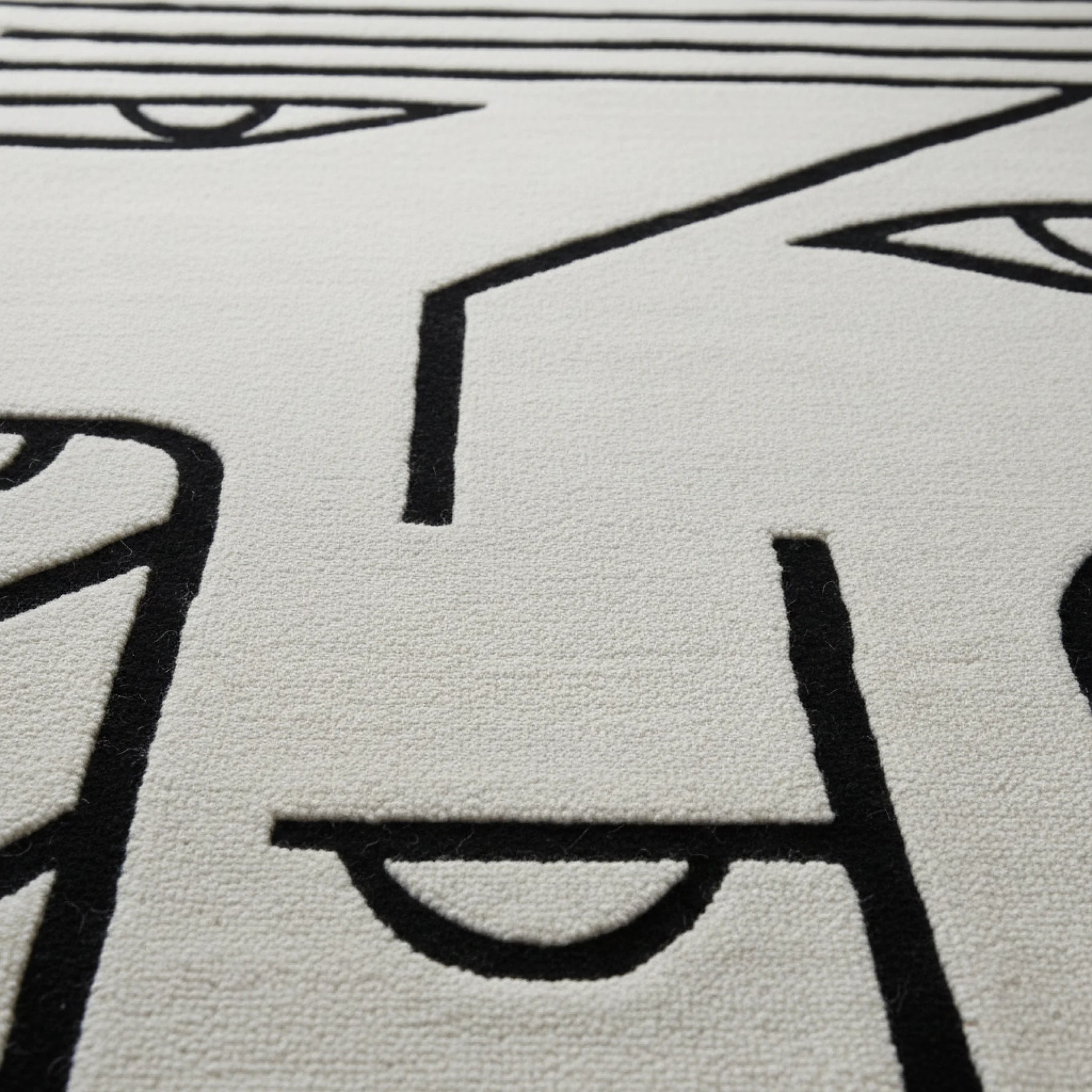 Close-up of a textured rug with black line art on a light gray background