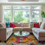 A vibrant and contemporary hand-knotted area rug enhances this cozy living room with its colorful interlocking tapestry design. Set beneath a sleek glass coffee table and surrounded by a plush sectional sofa adorned with colorful pillows, this area rug is a perfect statement piece for modern living rooms.
