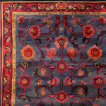 A beautifully intricate hand-tufted area rug featuring a vintage floral design. The rug showcases rich red and orange flowers with elegant vines on a deep blue background, perfect for adding a touch of elegance to large living room spaces. This wool rug combines classic and contemporary elements, making it an ideal choice for those seeking unique living room area rugs.