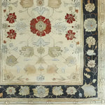 Close-up view of an Ivory Elegance Hand Knotted Area Rug, showcasing intricate floral patterns in red and beige tones with a dark border. Perfect for adding a touch of vintage charm to living rooms, this 8x10 Persian-style rug combines elegance and tradition.