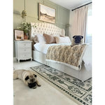 A cozy bedroom featuring a vintage-inspired wool rug beside a plush bed. The area rug, perfect for a large living room setting, adds a touch of elegance with its intricate design, making it ideal for those seeking living room rugs 8x10.