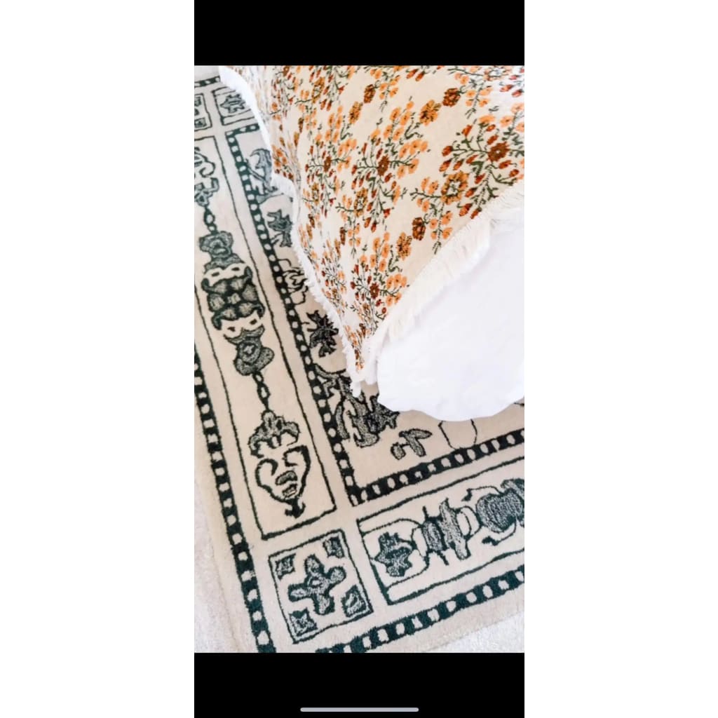 Close-up view of the Ivory Whispers hand-tufted area rug showcasing its intricate vintage design. The large living room rug, sized 8x10, features a detailed floral pattern in a soft ivory and green color palette, perfect for adding a touch of elegance to any space. Made from high-quality wool, this rug blends style and comfort seamlessly.