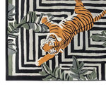 Top view of the Jade Tiger Threshold Hand Tufted Wool Rug, featuring a striking orange tiger design on a black and white geometric pattern, accented with green foliage. This area rug is perfect for adding a bold touch to your living room decor.
