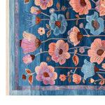 A vibrant Jeweled Garden Hand Tufted Wool Rug featuring a stunning floral pattern in shades of blue, pink, and purple. This area rug, ideal for living rooms, brings a touch of elegance and color with its intricate design and high-quality wool material, available in 8x10 size.