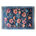 Jeweled Garden Hand Tufted Wool Rug showcasing a vibrant floral design in bold colors on a rich blue background. This 8x10 area rug is perfect for adding a touch of elegance to living rooms, blending the luxurious feel of a wool rug with the timeless appeal of floral patterns.