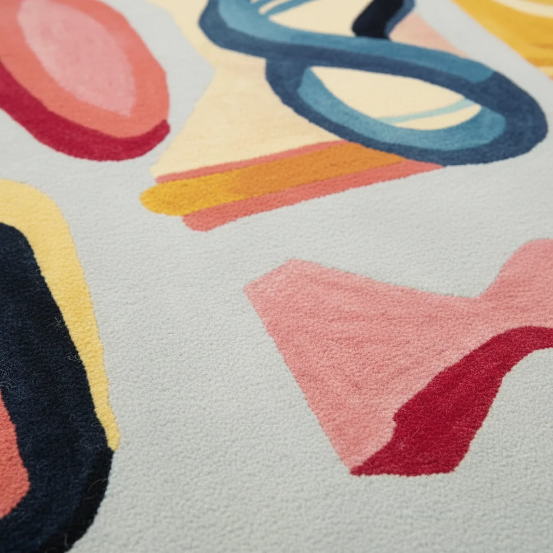 Joy Shape Parade Hand Tufted Area Rug featuring a vibrant abstract design in bold colors, perfect for adding a contemporary touch to your living room. This wool rug showcases a playful mix of shapes in shades of blue, yellow, pink, and red, ideal for modern rugs for living room decor.