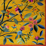 A vibrant area rug featuring an intricate floral design with colorful birds perched on branches, set against a rich mustard background. This hand-tufted wool rug is perfect for adding a splash of color to a living room, making it ideal for those seeking large living room rugs with a touch of nature.
