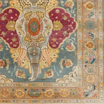 The Jumbo Jubilee Hand Knotted Area Rug features a vibrant and intricate design with a central elephant motif, surrounded by floral and geometric patterns. This vintage rug, perfect for large living rooms, showcases rich hues of teal, maroon, and gold, embodying the elegance of Persian rugs. Ideal for adding a touch of luxury to any living space.