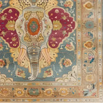 The Jumbo Jubilee Hand Knotted Area Rug features a vibrant and intricate design with a central elephant motif, surrounded by floral and geometric patterns. This vintage rug, perfect for large living rooms, showcases rich hues of teal, maroon, and gold, embodying the elegance of Persian rugs. Ideal for adding a touch of luxury to any living space.