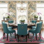Dining room with a round table and blue chairs, floral RUG, and a chandelier.