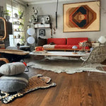 A stylish living room featuring a King of the Cats hand tufted wool rug with a tiger design, adding a unique touch to the hardwood floor. The area rug complements the modern decor, including a vibrant red sofa, abstract wall art, and an array of eclectic furnishings, perfect for dining room and living room spaces.