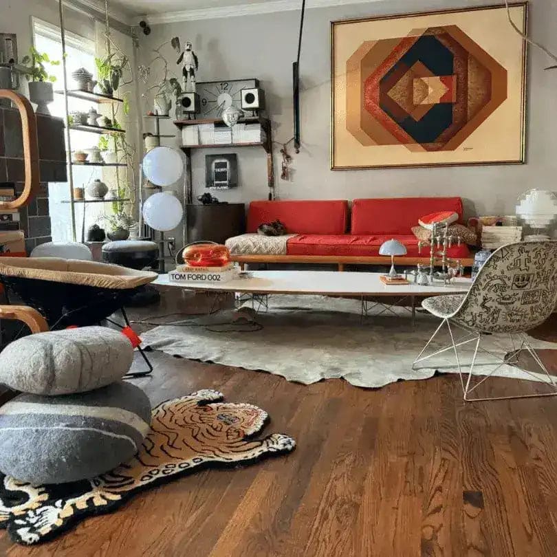 A stylish living room featuring a King of the Cats hand tufted wool rug with a tiger design, adding a unique touch to the hardwood floor. The area rug complements the modern decor, including a vibrant red sofa, abstract wall art, and an array of eclectic furnishings, perfect for dining room and living room spaces.