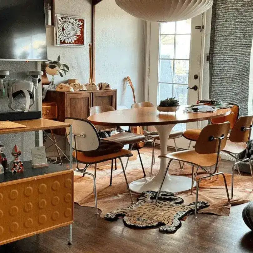 A cozy dining room featuring a unique King of the Cats hand-tufted wool area rug with an abstract tiger design. The rug adds a touch of whimsy to the modern decor, enhancing both the dining and living room spaces with its artistic flair.