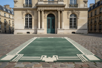 Green rug with white border in front of a classical building