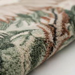 Close-up of a textured rug with green and brown patterns on a white background