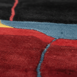 Close-up of a textured rug with red, blue, and black colors.