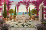 Woman sitting on a couch in a luxurious outdoor setting with an abstract floral wool rug, pink flowers and ocean view.