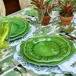 leafy lace placemats in white with green leaf sprig embroidery under stacked green plates on ikat cloth with plant pots