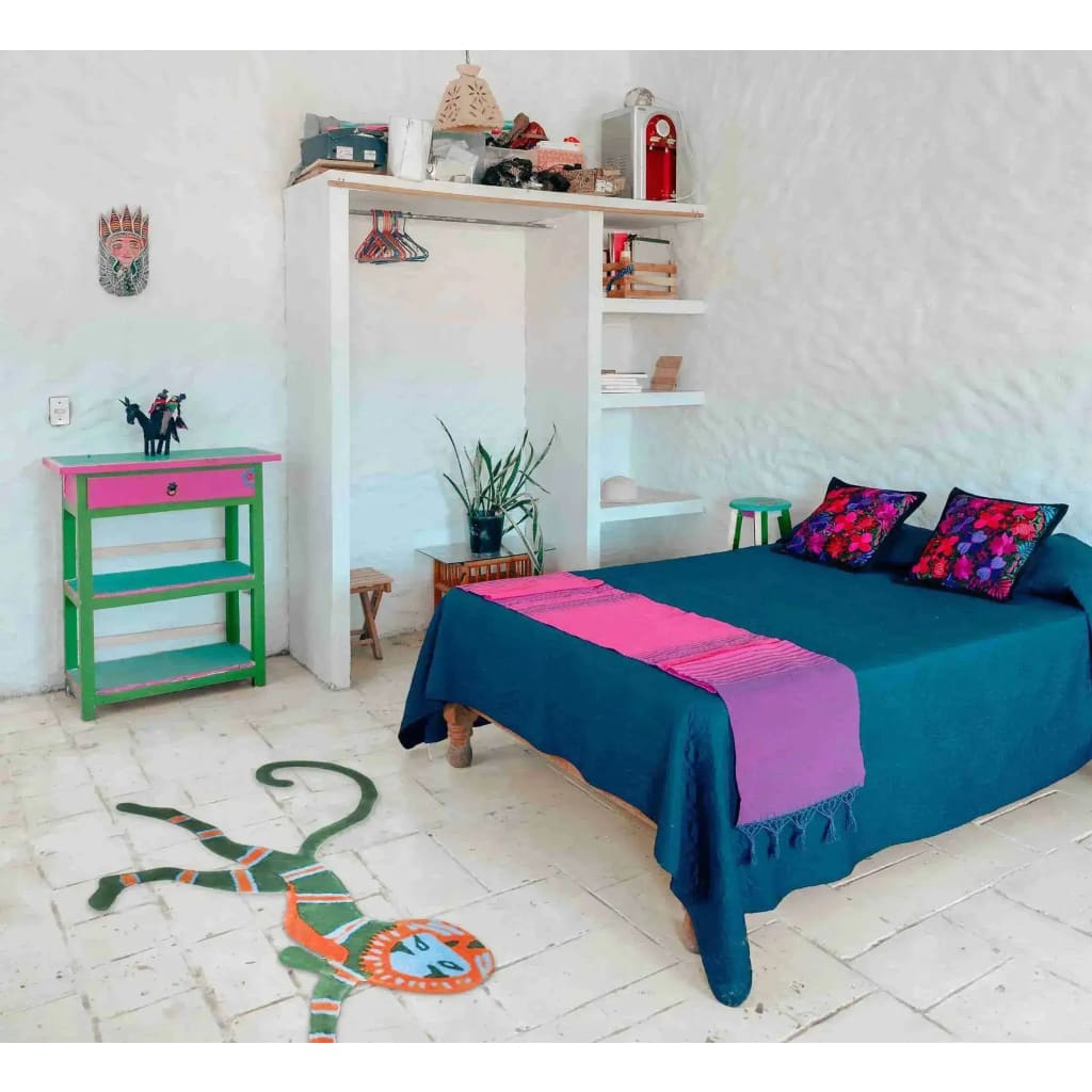 A vibrant wool rug featuring a leaping monkey design adds a playful touch to a bedroom. Placed on a light tiled floor, this vintage area rug complements the colorful decor and cozy atmosphere, making it an ideal choice for both dining room and bedroom spaces.