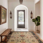 Foyer with a dark wooden door, floral persian hand knotted rug, and decorative elements.