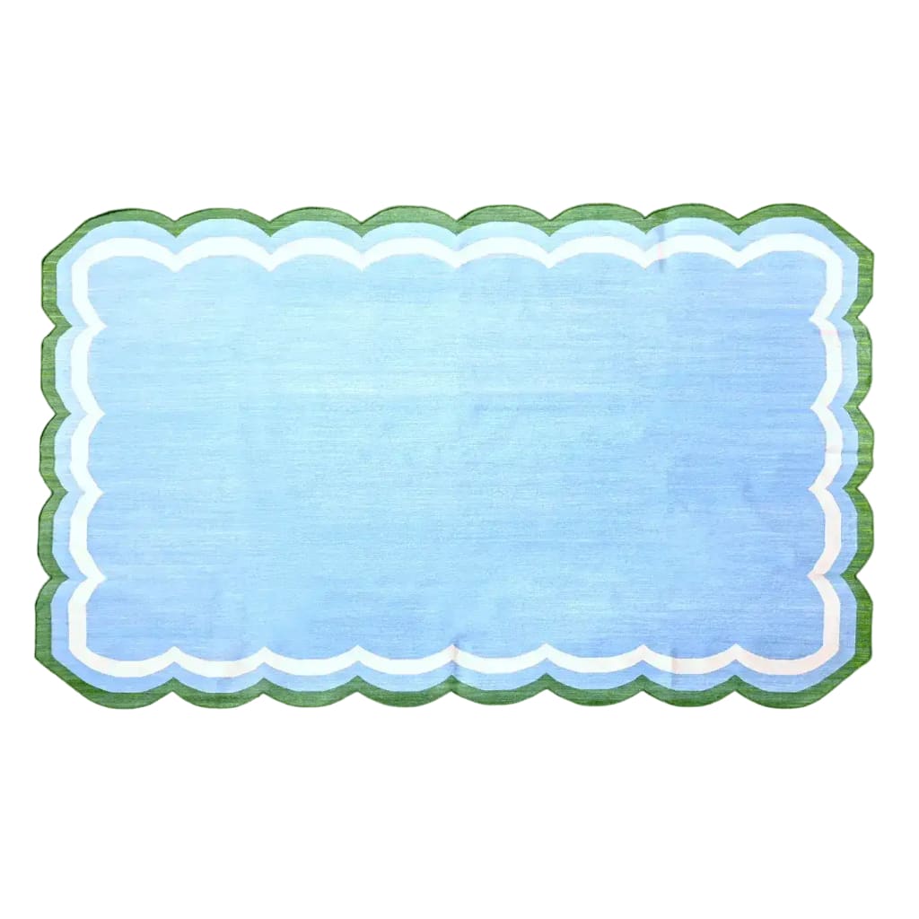 A light blue handmade reversible cotton area rug, measuring 3' x 5', featuring a charming scalloped edge. Perfect for adding a boho touch to your living room, this rug showcases a soothing blue hue with green and white accents, making it an ideal choice for living room area rugs or as a centerpiece in any space.