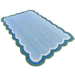 Light blue handmade reversible cotton area rug with scalloped edges, perfect for adding a boho touch to your living room. This 3' x 5' rug features gentle blue tones bordered by green and white, making it an ideal choice for those seeking stylish and cozy living room area rugs.