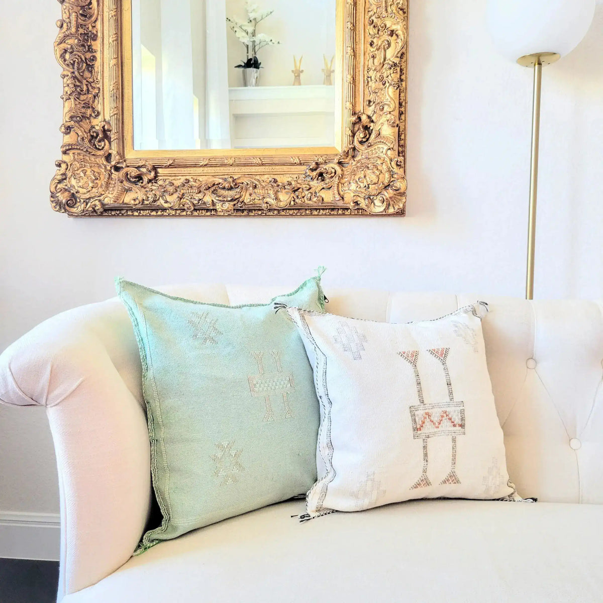 Light green handwoven cactus silk throw pillow cover on a white couch, paired with a decorative white pillow, enhancing a stylish living room decor.