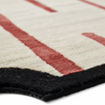 Close-up of a geometric-patterned rug with red, black, and white colors.