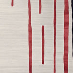Close-up of a contemporary wool area rug featuring bold red linear patterns on a soft beige background, perfect for adding modern elegance to living room spaces.