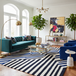 Modern living room with teal sofa, striped rug, and decorative elements.
