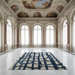 Large room with classical architecture featuring a blue and beige patterned rug on a marble floor.