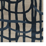 A close-up view of a contemporary hand-tufted wool area rug, featuring an abstract design with bold, dark blue intersecting lines on a light beige background. This large living room rug adds a modern touch to any space, making it an ideal choice for those seeking stylish living room area rugs.
