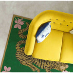 Top view of a vibrant green area rug featuring an abstract tiger design, placed partially under a yellow sofa in a stylish dining room setting. The wool rug adds a boho touch, making it ideal for large living room and dining room spaces.