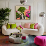 A vibrant living room featuring a Lotus Horizon Hand Tufted Area Rug with abstract designs, adding a contemporary flair. This wool rug complements the stylish decor, including a plush white sofa with colorful cushions, a mirrored coffee table, and a bright pink ottoman, creating an inviting space for modern living.