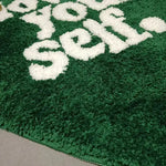 Close-up of a plush green area rug with the phrase 'Love Your Self' in white letters, perfect for adding a cozy touch to living room decor. Ideal for those seeking stylish area rugs for living room settings.