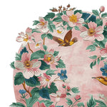 A beautifully detailed area rug showcasing a vibrant floral design with pink and white blossoms, lush green leaves, and birds, set against a soft pink background. This round wool rug is perfect for adding a touch of elegance to any living room.