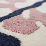 Close-up of a colorful geometric-patterned rug with pink, blue, and white colors.