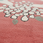 Close-up of a pink textured surface with white floral patterns wool rug