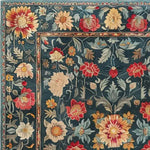 Close-up view of the Lush Petals Hand Tufted Area Rug, showcasing its intricate floral design in vibrant reds, yellows, and greens against a rich teal background. Perfect for adding a touch of vintage elegance to living room or dining room spaces, this wool rug exudes warmth and style.