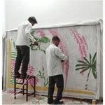 Artisans meticulously crafting a made-to-order hand-tufted wool rug, perfect for dining rooms and living room areas. The vibrant design, featuring green and pink patterns, illustrates the care and expertise involved in creating a luxurious area rug.