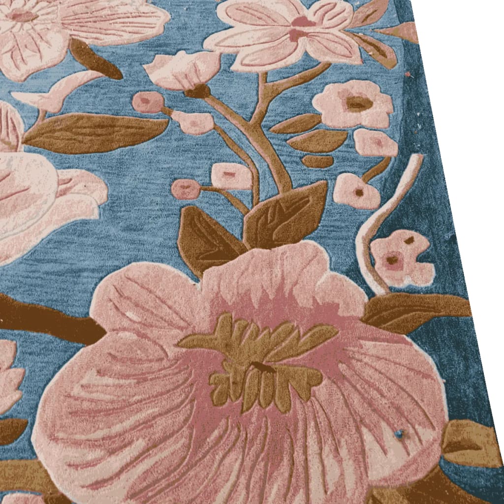 Close-up view of the Magnolia Blossom Hand Tufted Area Rug, showcasing its intricate floral design with pink and brown blossoms on a blue background, perfect for enhancing a dining room or large living room. This wool rug adds a touch of elegance to any living space.