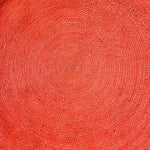 Top view of a vibrant red, round jute area rug with a woven texture, perfect for adding a splash of color to large living room spaces. This stylish living room area rug highlights intricate craftsmanship, ideal for those seeking unique large area rugs.